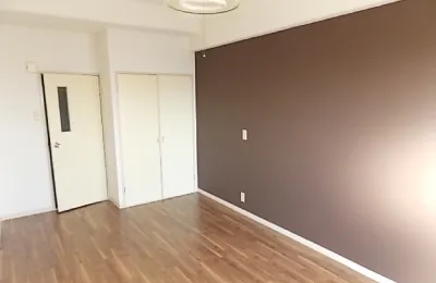 木目調のフローリングが広がる室内で、片側にブラウンのアクセントクロス壁を設けたシンプルな居室