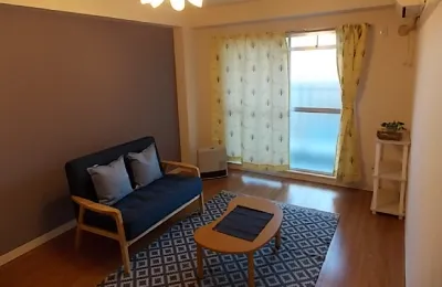 ソファとローテーブルを配置したリビングルームで、アクセントクロスの壁とラグが落ち着いた雰囲気を演出している室内