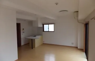 白を基調とした広々としたリビング空間で、対面式キッチンとフローリング床が一体となった明るい室内の様子